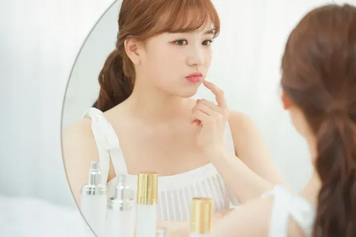 鏡の前で口を気にする女性