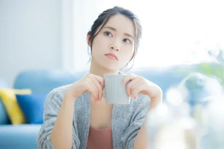 マグカップを手に悩む女性
