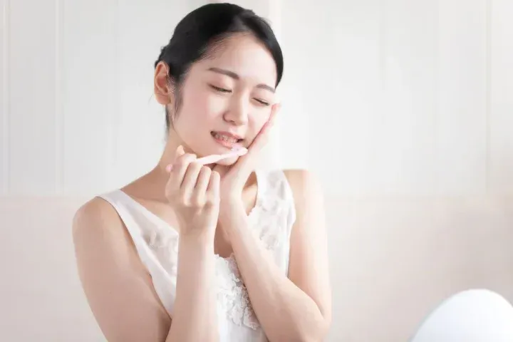 歯磨きをしながら歯が痛そうな女性