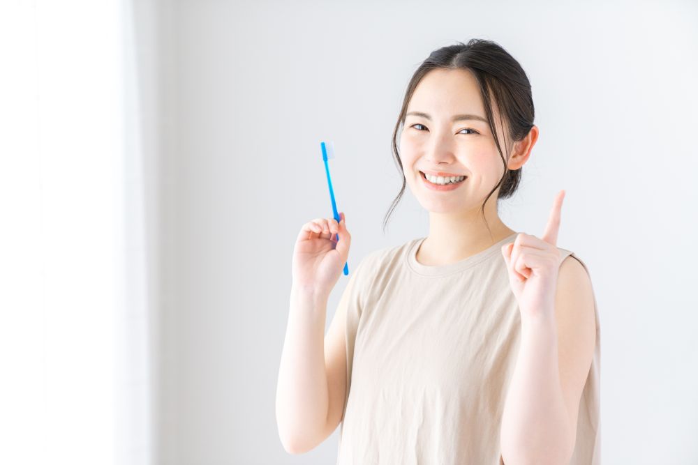 歯ブラシを片手に微笑む女性