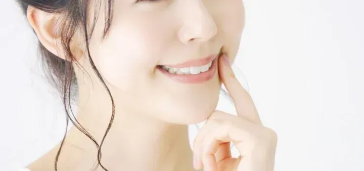 口元を指さす女性