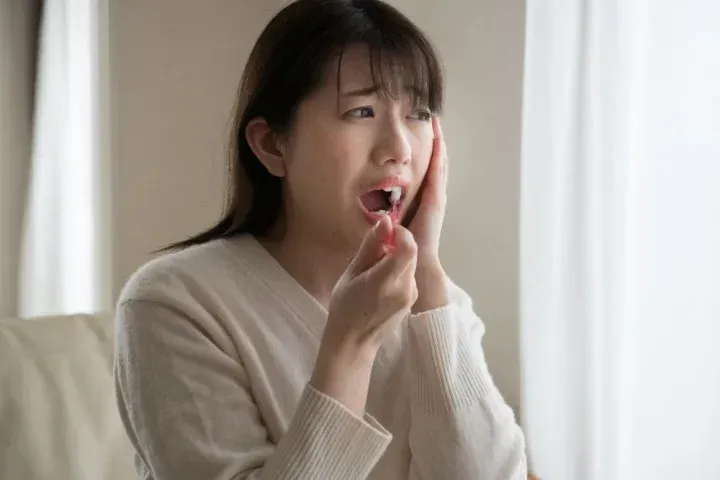 歯磨きをしながら口の中に痛みを感じる女性