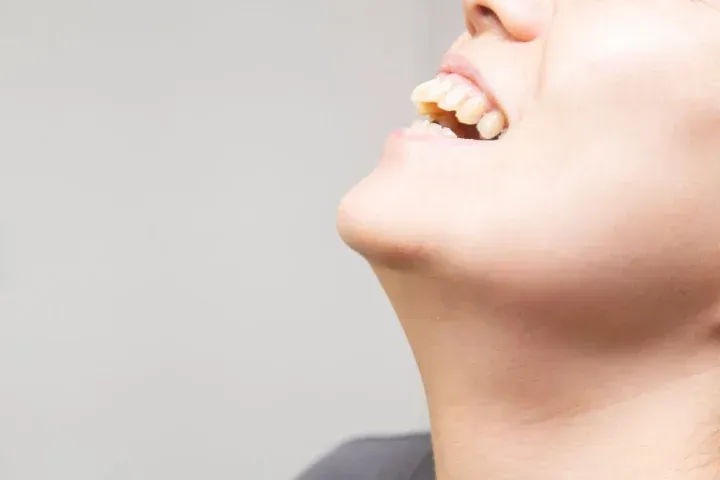 上を向いて笑う人の口元