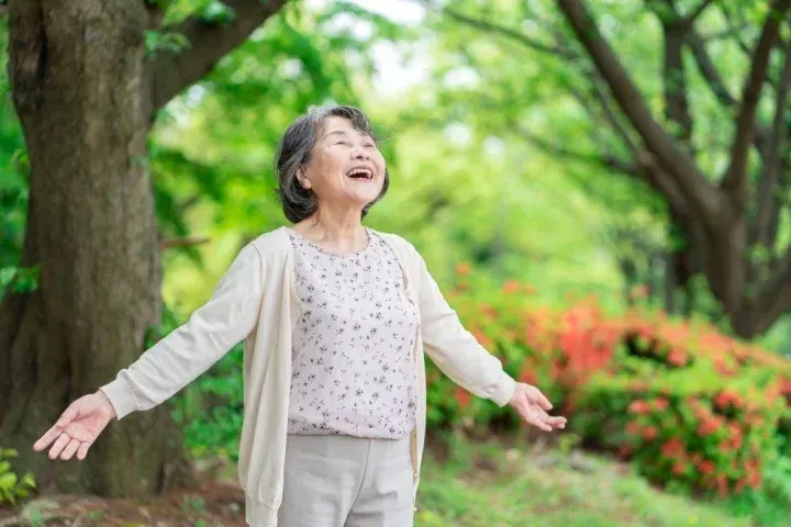 自然の中で深呼吸をする老人