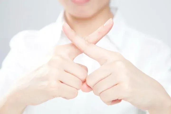 指で×をする様子